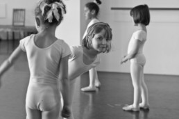 Young girl pokes out from among a group of young ballerinas