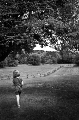 A young girl walks alone in a field.