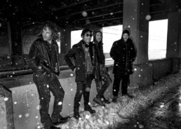 The Ember Glows band posing under an ovepass on a snowy day.